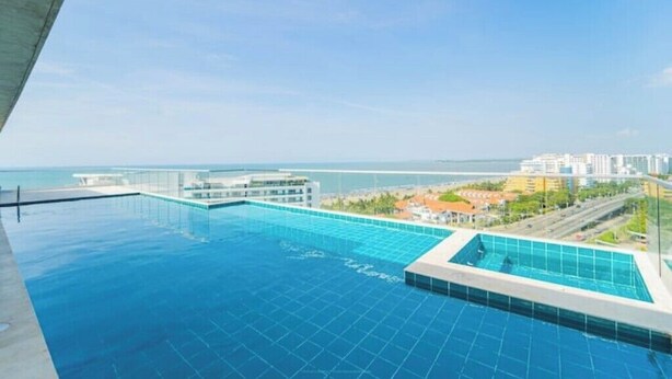 A rooftop infinity pool with a clear view of the ocean and cityscape.