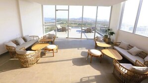 A spacious balcony with wicker furniture, large windows offering a view of the cityscape.