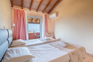 Une chambre avec deux lits, une fenêtre avec des rideaux, un appareil de climatisation et une vue sur l’extérieur.