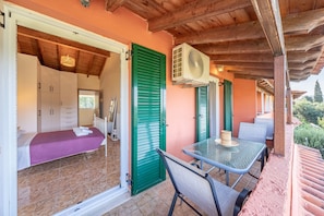 Une pièce avec un lit, une table et des chaises, un ventilateur et une fenêtre.