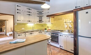 A kitchen with white cabinets, a wooden countertop, a gas stove, and a built-in oven. - Country House 'Sestadors' with Private Pool, Wi-Fi and Air Conditioning (Illes Balears)