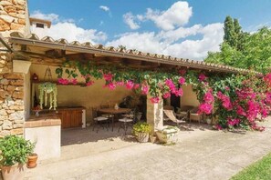 A covered patio with a table and chairs, surrounded by potted plants and flowering vines. - Country House 'Sestadors' with Private Pool, Wi-Fi and Air Conditioning (Illes Balears)