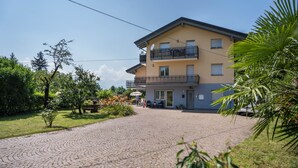 A two-story building with a paved driveway, outdoor seating, and a balcony.