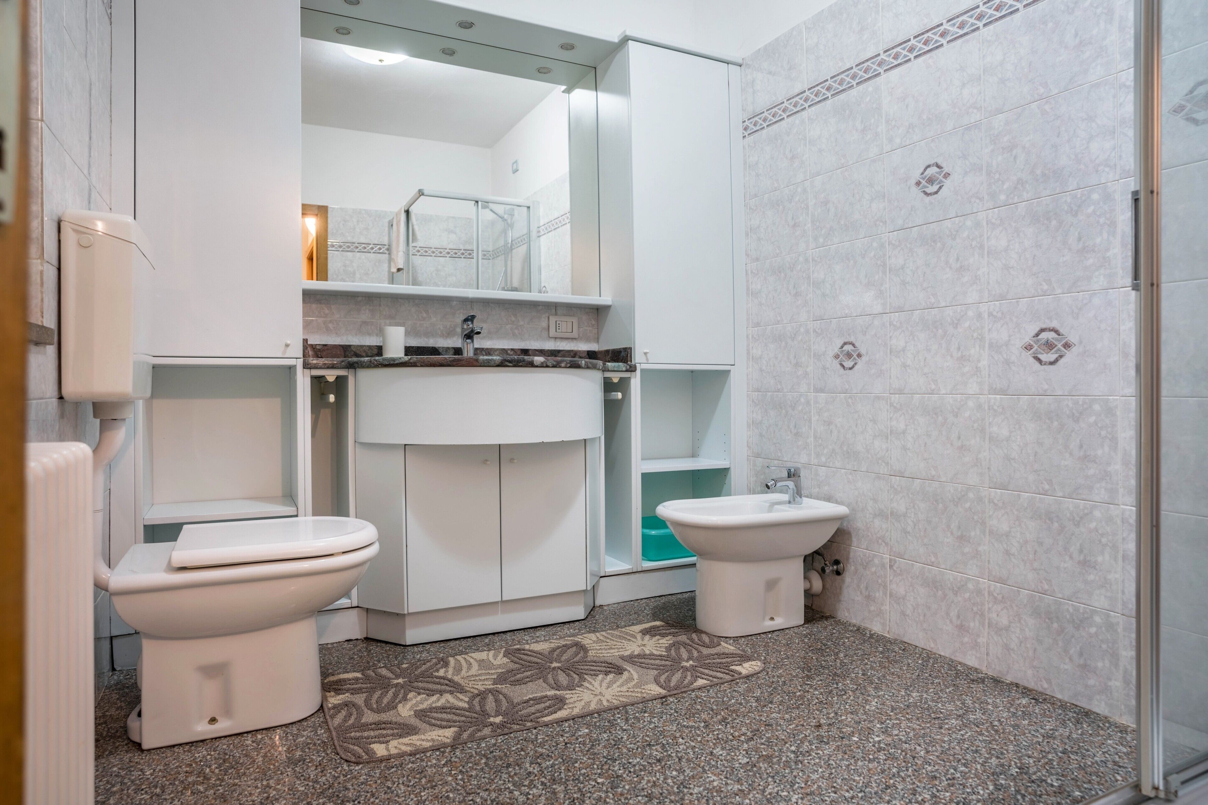 Ein Badezimmer mit zwei Toiletten, einem Waschbecken und einer Dusche.