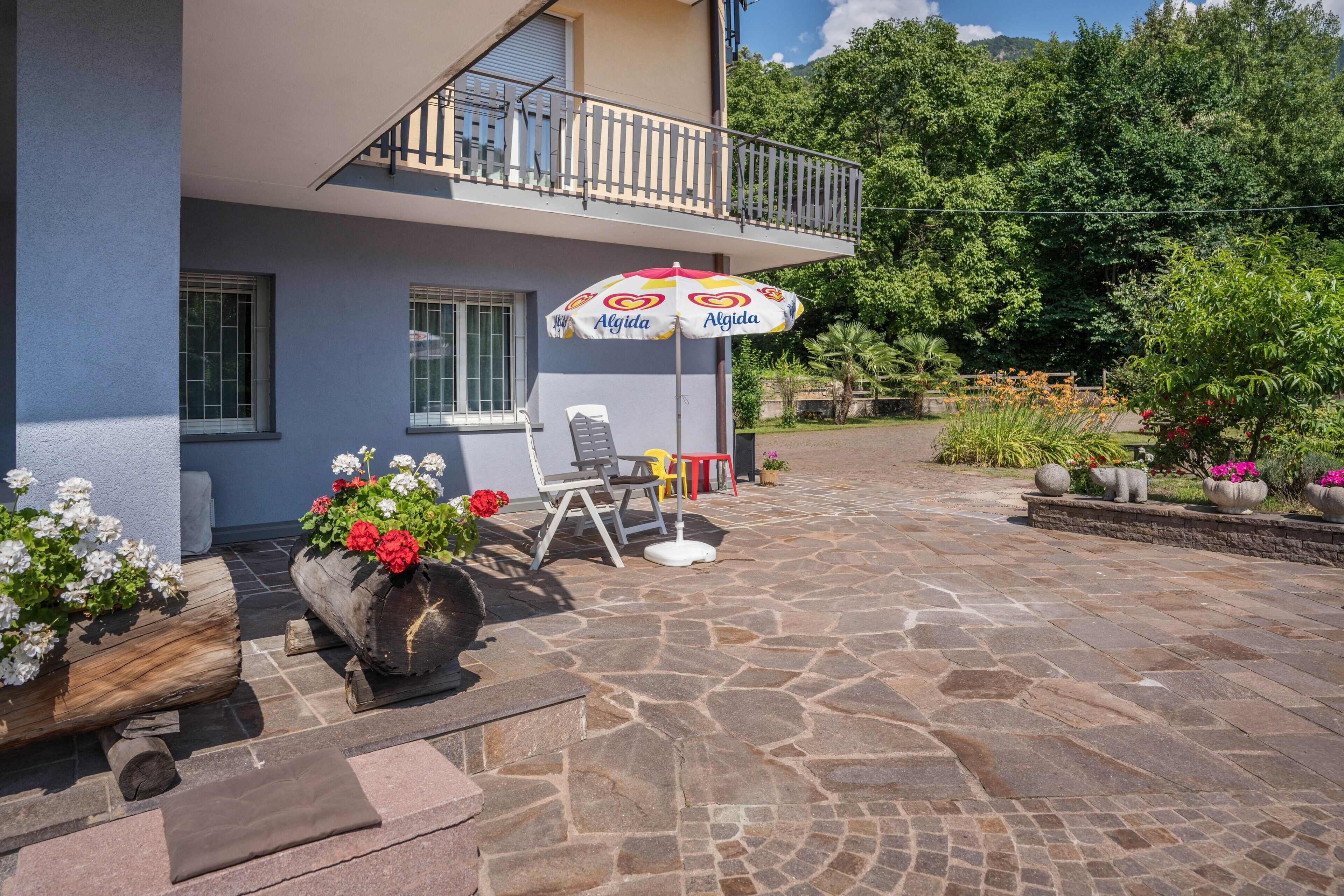 Ein Gebäude mit Balkon, Außenbereich und Pflanzkübeln.