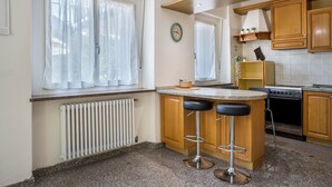 A kitchen with wooden cabinets, a built-in stove, a clock, and a window with curtains.