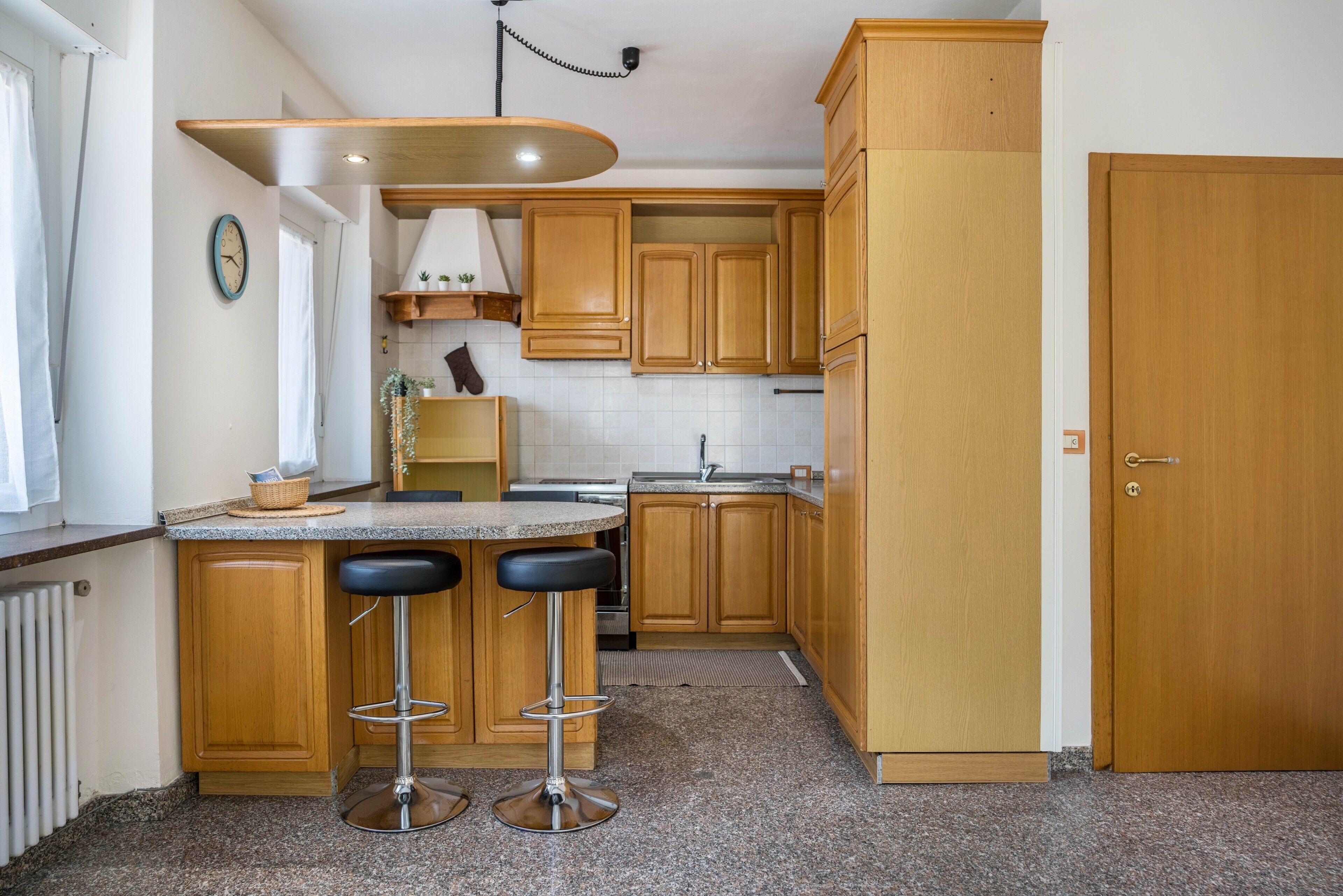 Una cucina con mobili in legno, un piano di lavoro, un lavello e una porta.