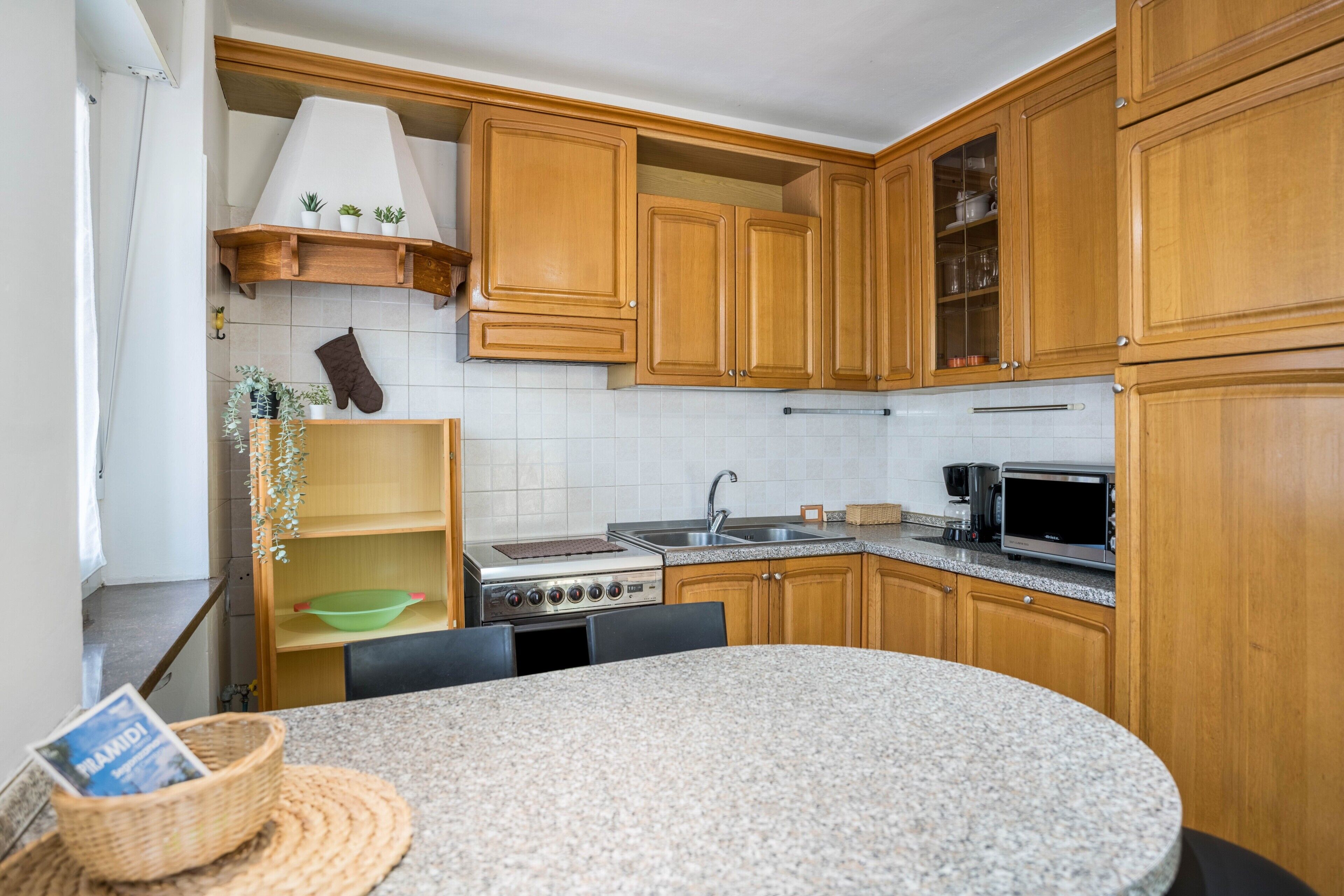 Een keuken met houten kastjes, een fornuis, een magnetron en een spoelbak.