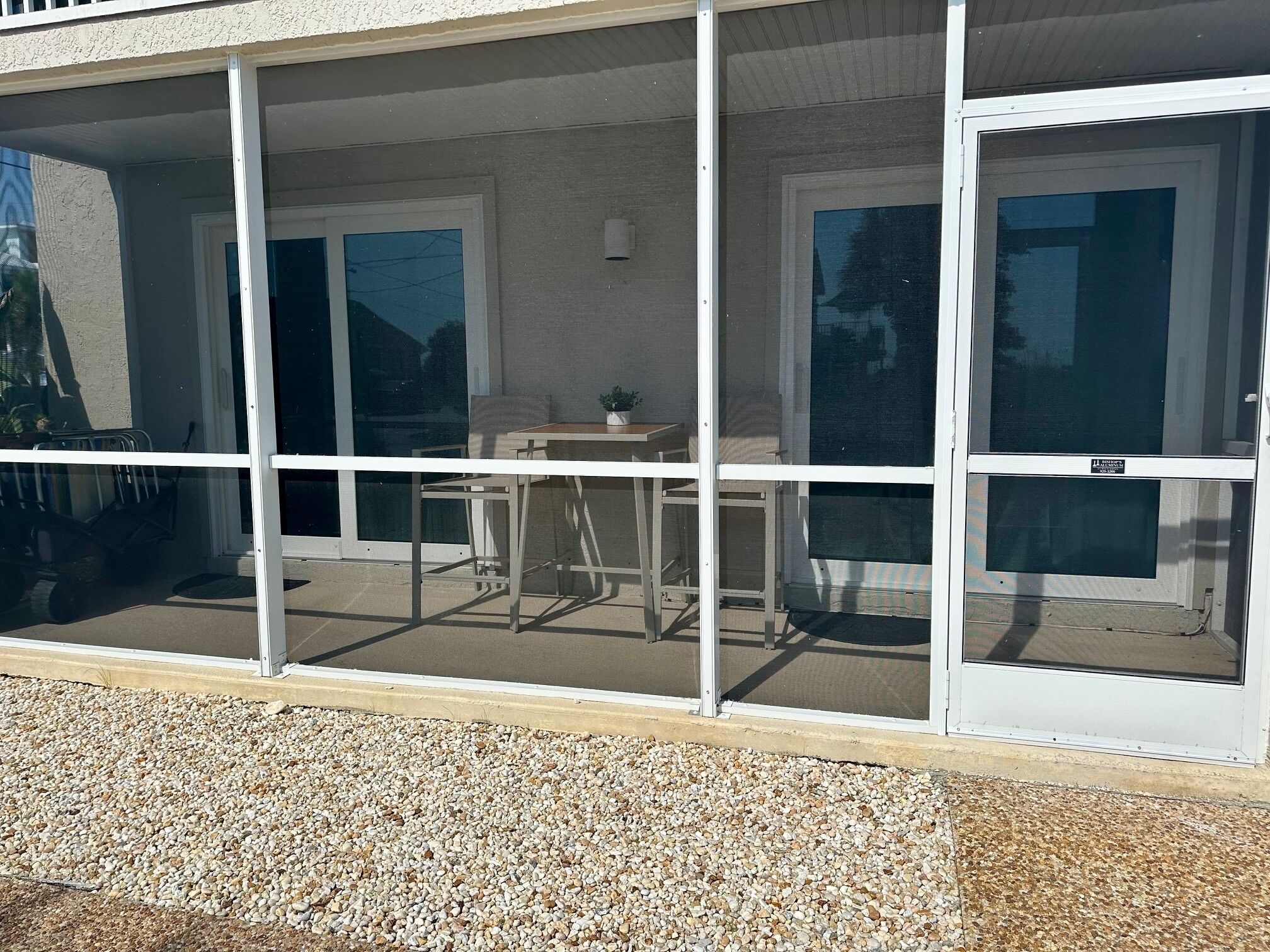 A covered patio area with a table and chairs, a small potted plant, and a door leading to the interior.