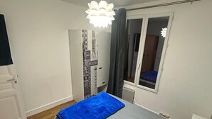 A bedroom with a bed, a window, a door, and a ceiling light.