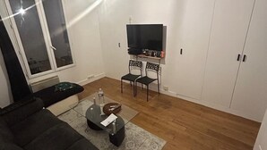 A living room with a sofa, a TV, and a small table with a remote.