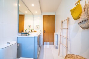 A bathroom with a toilet, sink, mirror, wooden door, and a towel rack with two towels. - Villa 'Es Tancat' with Sea View, Private Pool and Wi-Fi (Sa Ràpita)