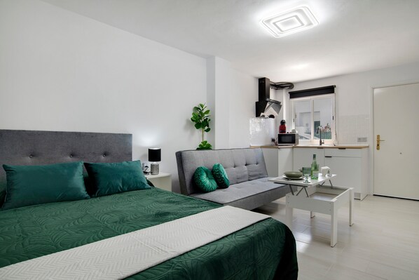 Une chambre moderne comprenant un lit, un canapé, une petite table et un coin cuisine.