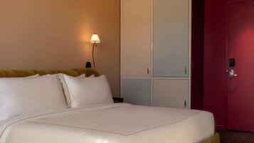 A neatly made bed with white linens, a bedside lamp, and a wardrobe with sliding doors.