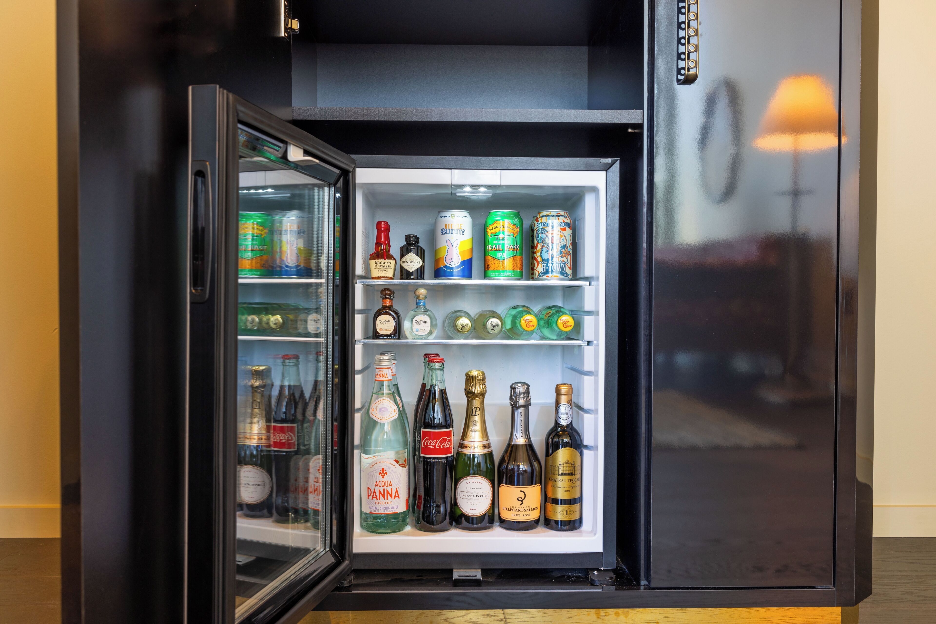 A mini-fridge stocked with various beverages including bottles and cans.