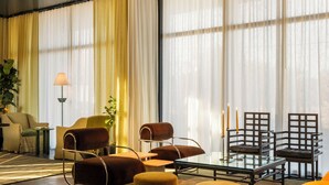 A modern living room with a glass coffee table, leather armchairs, and a sofa. There are candles on the table and a lamp on a side table. - Hotel Saint Augustine (Houston)