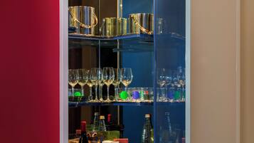 A glass-fronted cabinet with shelves containing various glassware and bottles.
