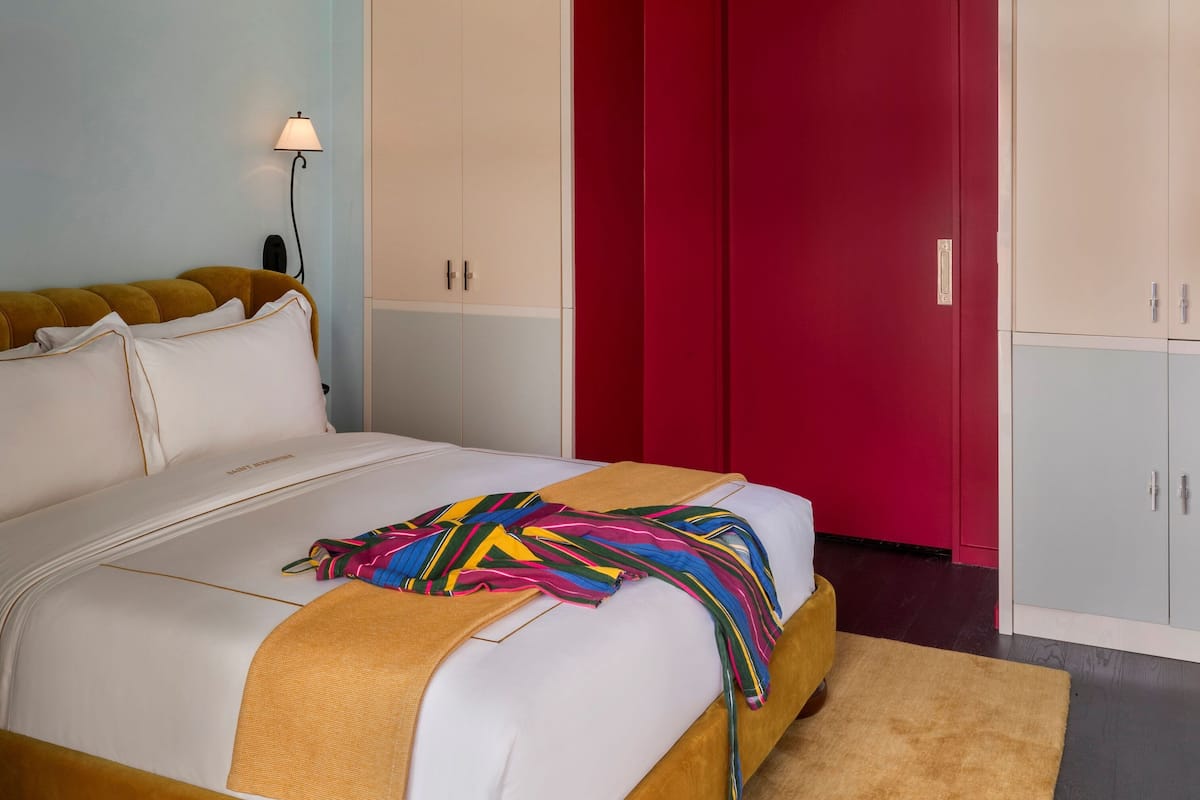 A modern bedroom with a bed, a red wardrobe, and a ceiling light.