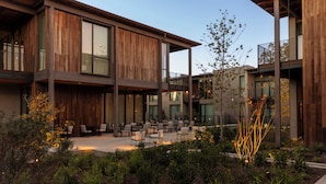 A modern building with multiple floors, large windows, and a courtyard with outdoor seating. - Hotel Saint Augustine (Houston)