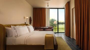 Une chambre d’hôtel avec un grand lit, un canapé, une petite table et une vue sur l’extérieur grâce à une porte coulissante.