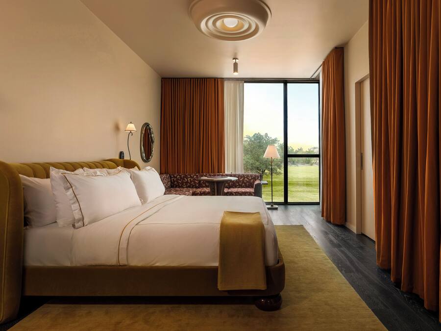 Une chambre d’hôtel avec un grand lit, un canapé, une petite table et une vue sur l’extérieur grâce à une porte coulissante.