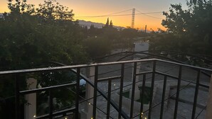 A rooftop terrace with a metal railing, a view of the sunset, and some greenery. - Masia Bernat: Antigua Masía en la Naturaleza Para Grupos (Tortosa)