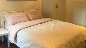 Ein Schlafzimmer mit Bett, Nachttisch, Kleiderschrank und einem Bild an der Wand.