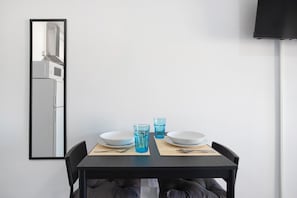 Una mesa de comedor con dos platos blancos, dos vasos azules y una silla negra.