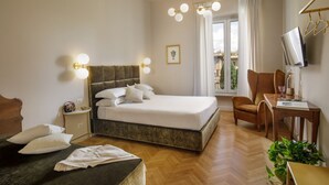 A hotel room with a large bed, a desk, a chair, a TV, and a window with curtains.