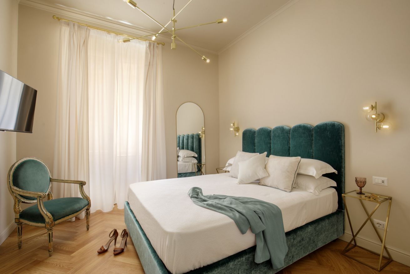 A bedroom with a large bed, a chair, a television, and a bedside table.