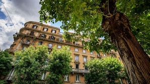 A multi-story building with balconies, surrounded by trees.