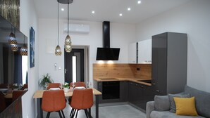 Een moderne keuken met een houten aanrecht, zwarte kastjes en een grijze bank met een geel kussen.