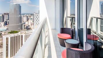 A balcony with wicker furniture and a city view.