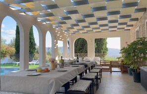 Un espace repas comprenant une longue table, des chaises et une vue sur l’extérieur.