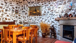 A stone-walled room with a dining table, chairs, a fireplace, and a painting on the wall. - Country House 'Casa Rural Del Tormes' with Mountain View, Private Terrace and Private Garden (Puente del Congosto)