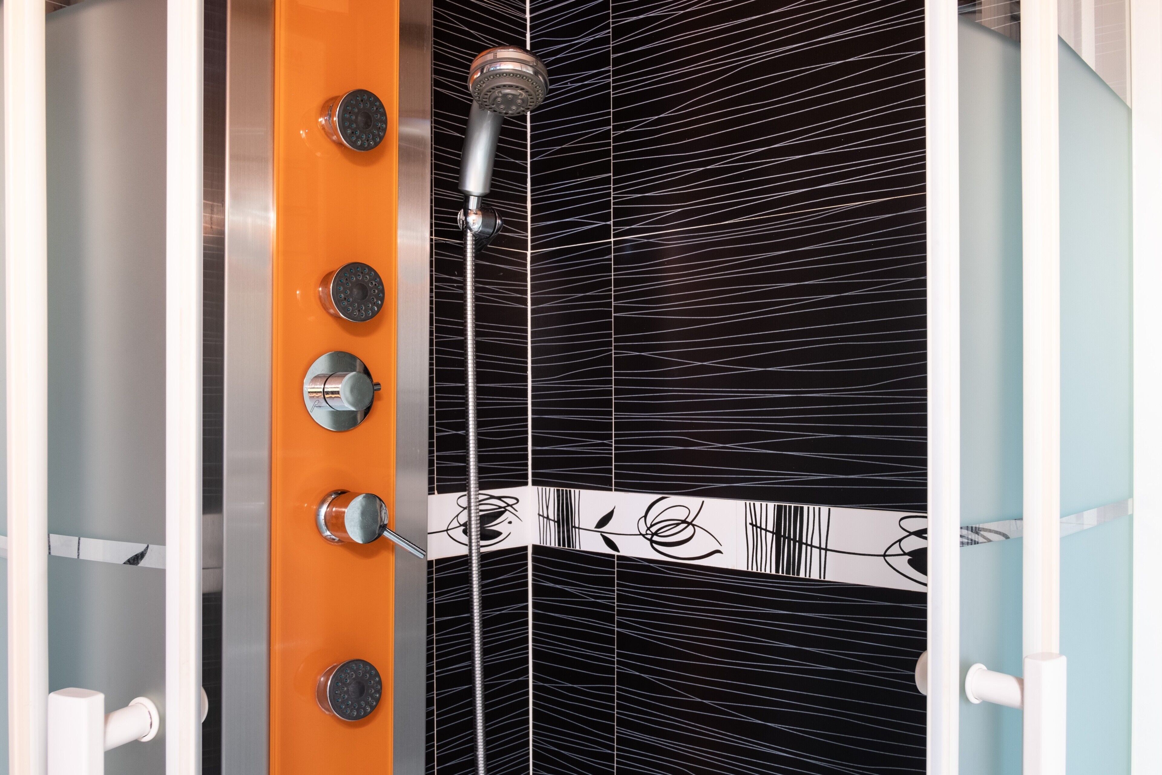 A shower with a modern design, featuring a vertical handle and multiple control knobs.
