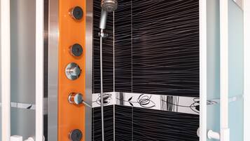 A shower with a modern design, featuring a vertical handle and multiple control knobs.