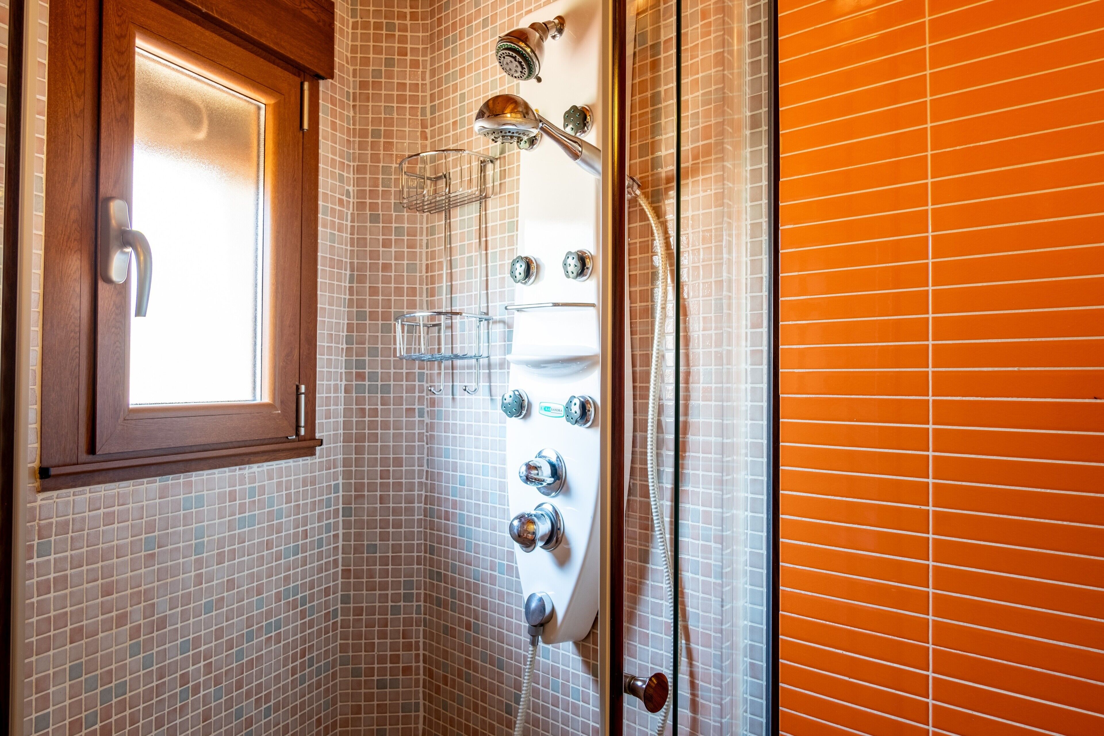 A bathroom with a shower, a window, and a tiled wall.