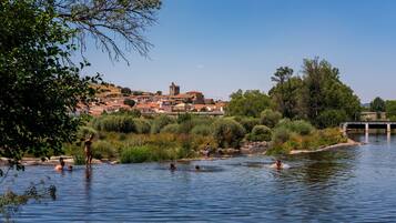Une rivière où des gens se baignent, un pont et une ville avec des bâtiments en arrière-plan.