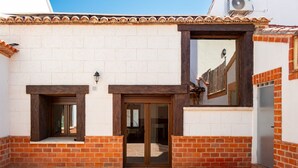 Un bâtiment avec un toit en tuiles, une façade en briques et une grande fenêtre.