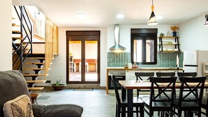 Une cuisine moderne avec un coin repas, un escalier en bois et un canapé agrémenté d’un coussin décoratif.