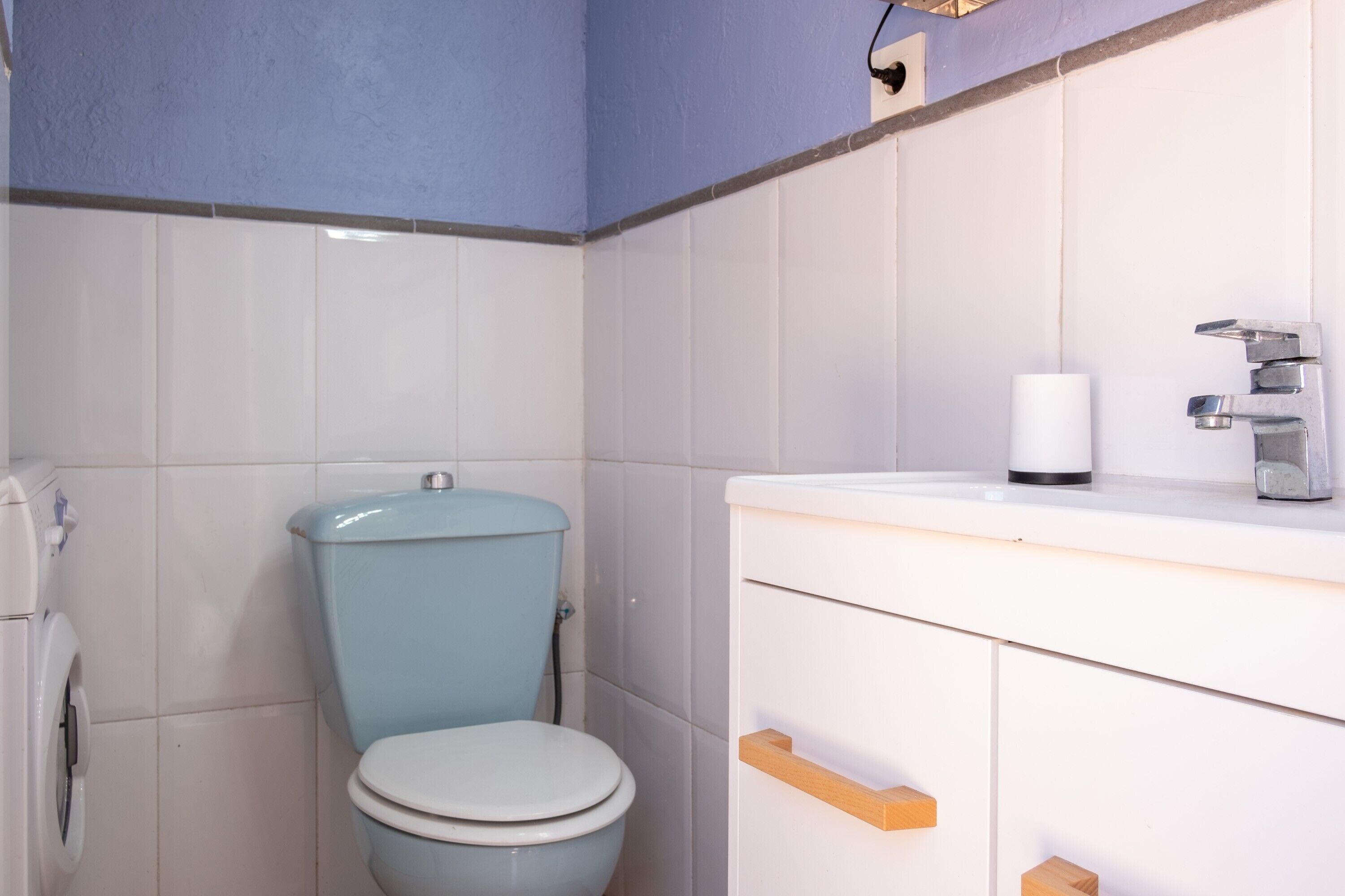 Un baño con inodoro, lavamanos y soporte para papel higiénico.