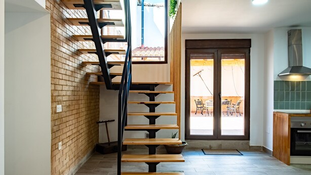 Un escalier avec des marches en bois et une rampe en métal, menant à un balcon d’où l’on peut admirer la vue.