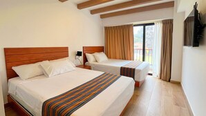 Ein Hotelzimmer mit zwei Betten, Holz-Kopfteilen, einem großen Fenster mit Vorhängen und einem an der Wand befestigten Flachbildfernseher.