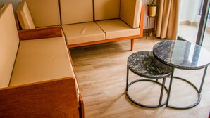 Ein modernes Wohnzimmer mit einem beigefarbenen Sofa, einem Holztisch und einer Topfpflanze.
