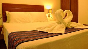 Ein Hotelzimmer mit einem ordentlich bezogenen Bett, einer gestreiften Tagesdecke und einer Wandlampe.