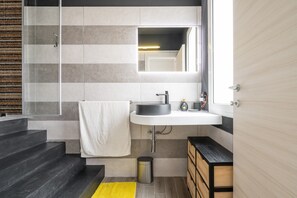 A modern bathroom with a large mirror, a white sink, and a shower area. - Apartment 'Home 101' with Sea View, Wi-Fi and Air Conditioning (Calasetta)