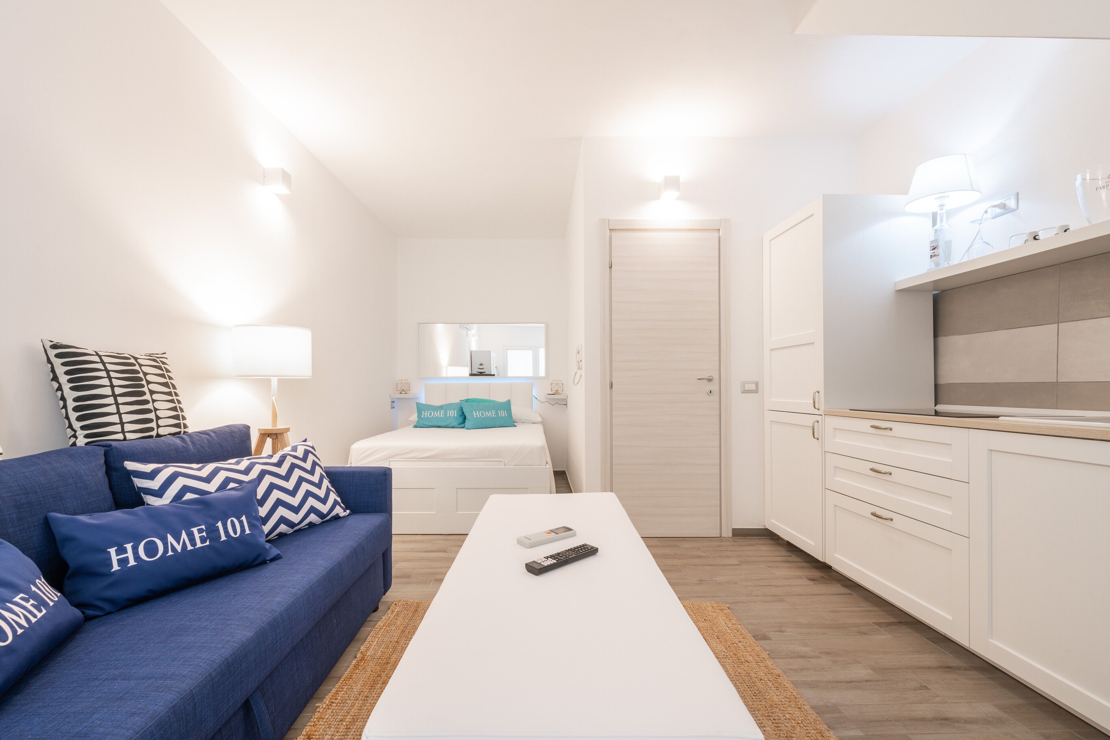 A compact living space with a sofa, a coffee table, a bed, and a kitchenette.