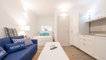 A compact living space with a sofa, a coffee table, a bed, and a kitchenette.