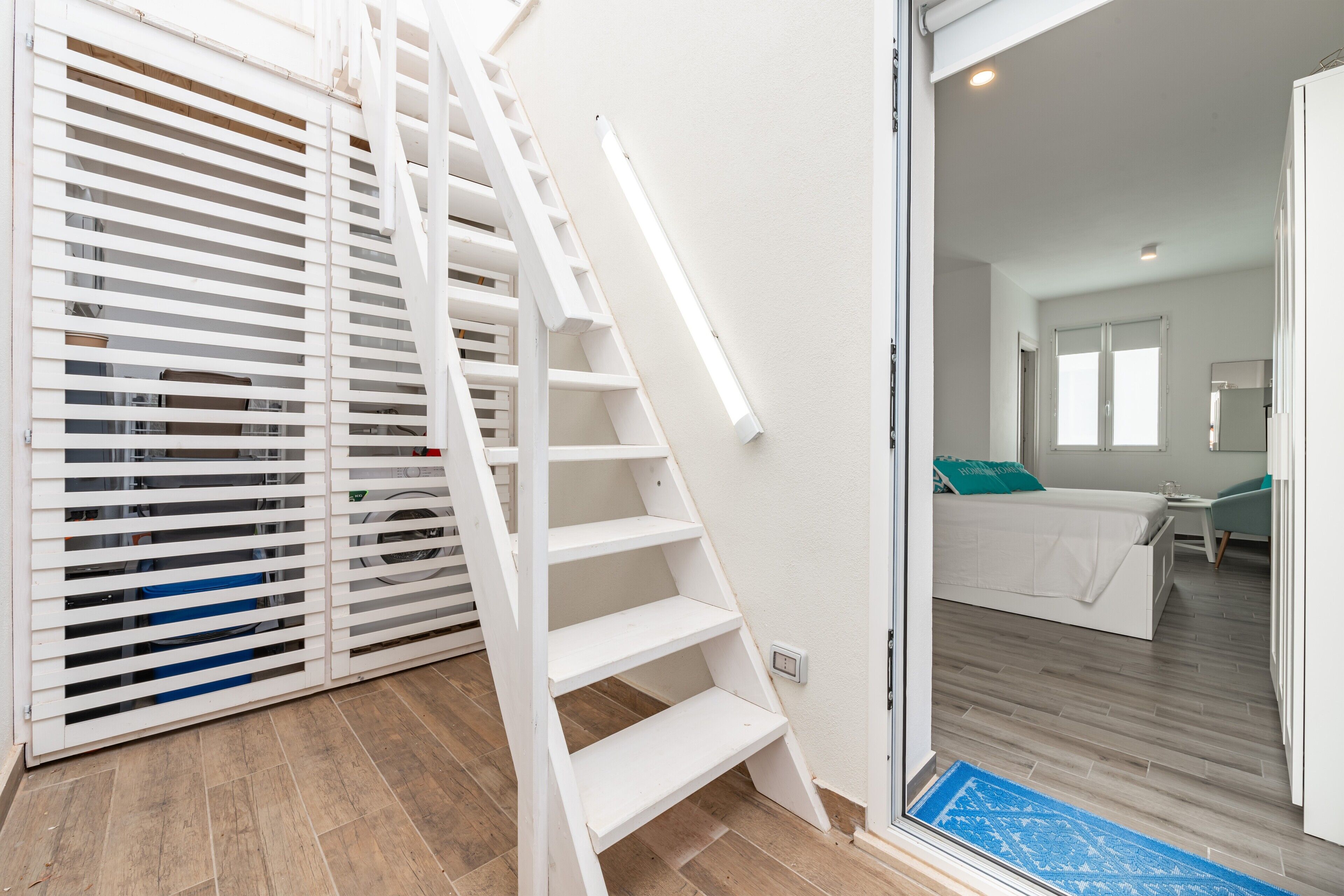 A staircase leading to a bedroom with a bed, a small table, and a chair.